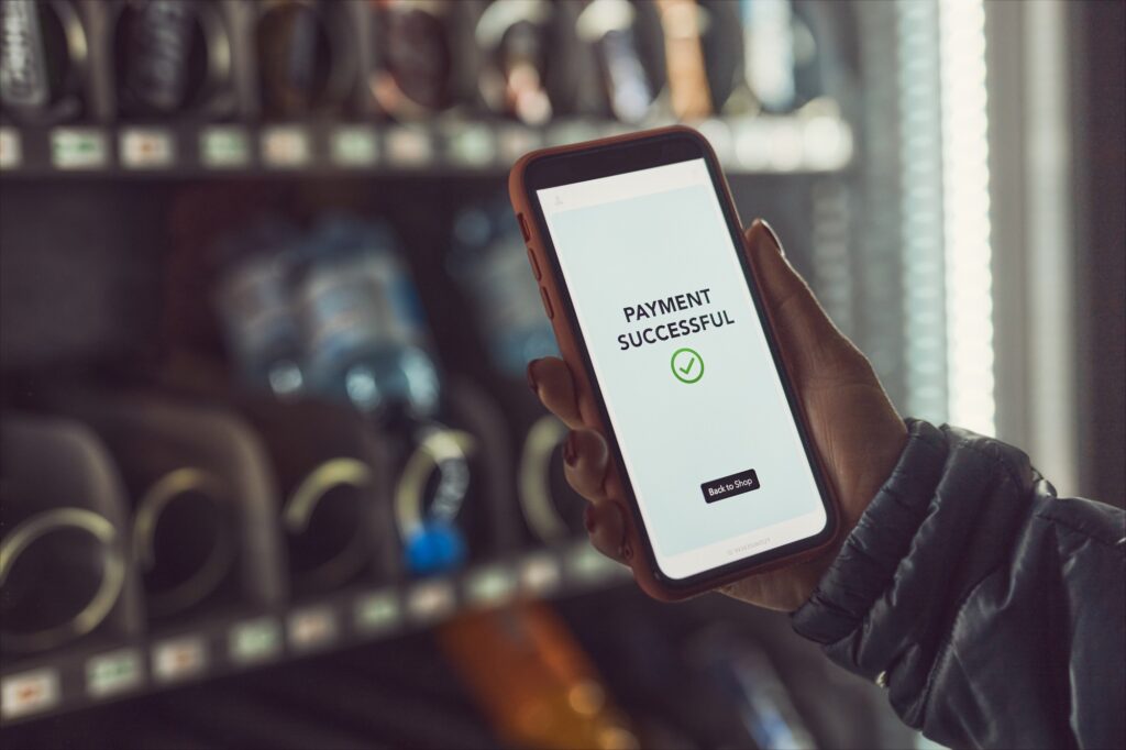 A mobile phone payment  is made for a snack from a food and soda vending machine